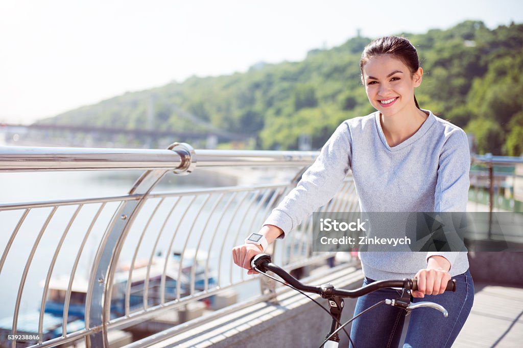 Young woman looking at camera Feeling happiness. Smiling young woman looking at camera and holding handles of a bicycle Adult Stock Photo