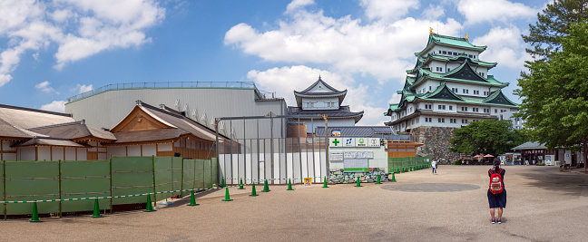 Nagoya, Japan - May 13, 2016: a visitor takes a picture of the main tower of the Nagoya castle; to the left the restoration site of the Hommary Palace.