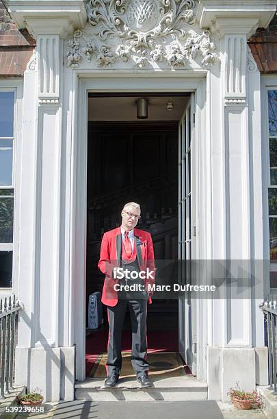 Típico Inglés Hombre Parado En La Puerta Con Llave Foto de stock y más banco de imágenes de Mayordomo - Mayordomo, Rojo, 40-44 años