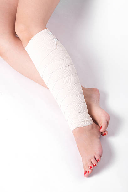caviglia donna su uno sfondo bianco strappati fasciatura elastica - human knee physical injury bandage muscular build foto e immagini stock