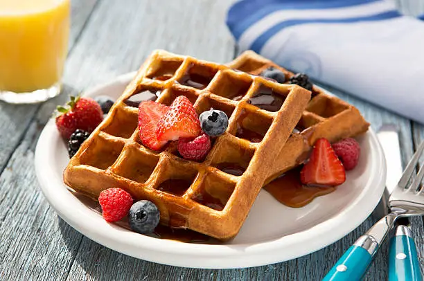 Waffles with fruit on a rustic table top.