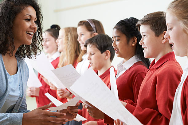 crianças na escola coro ser encorajado pelo professor - sheet music music classroom education - fotografias e filmes do acervo