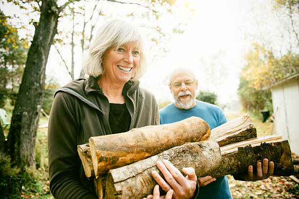 casal idoso empilhar lenha no quintal - gardening senior adult action couple imagens e fotografias de stock