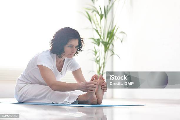 Beautiful Caucasian Woman Doing Yoga Exercise Stock Photo - Download Image Now - One Woman Only, Sitting On Ground, Stretching