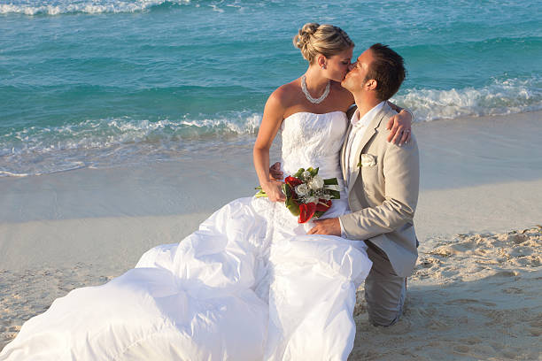 Full length of romantic groom carrying bride while walking on beach. Horizontal shot.