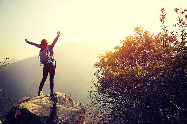 istock cheering woman hiker open arms at mountain peak 539258805