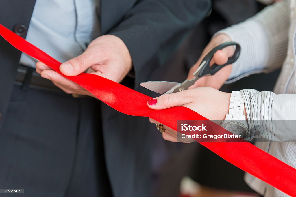 Opening ceremony with ribbon cutting Woman is cutting a red ribbon with scissors. Office Stock Photo