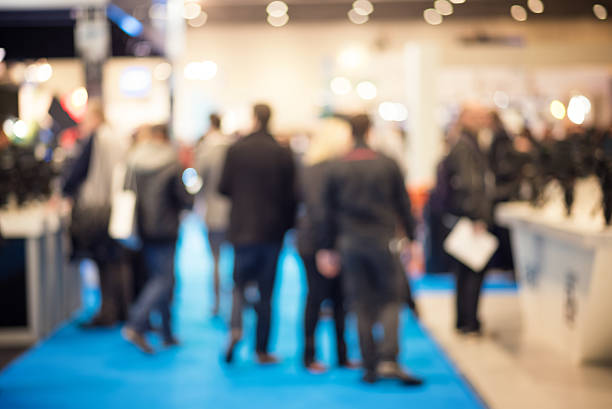 People at a Trade Exhibition Defocused shot of crowd  on exhibition. Purposely blurred with a lens. kiosk stock pictures, royalty-free photos & images
