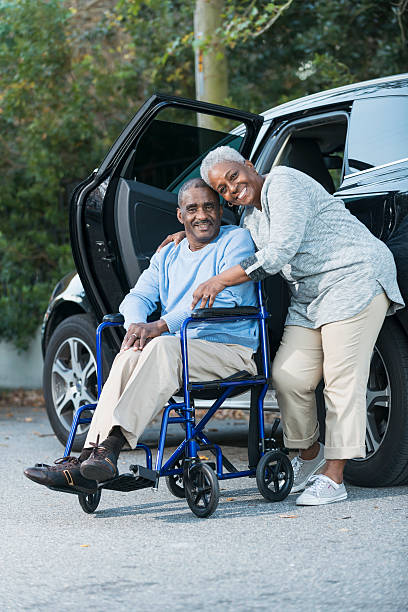 senior pareja de hombre en silla de ruedas al lado del coche - couple dependency standing men fotografías e imágenes de stock
