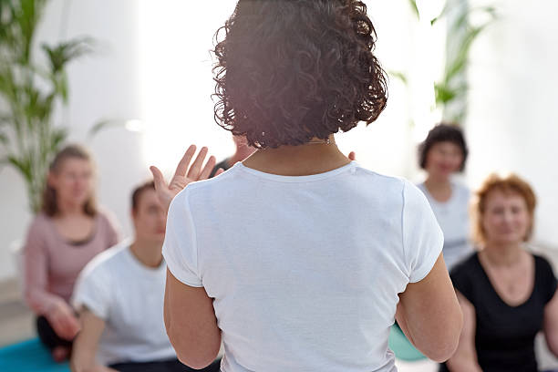 Female instructor guiding student during yoga class stock photo