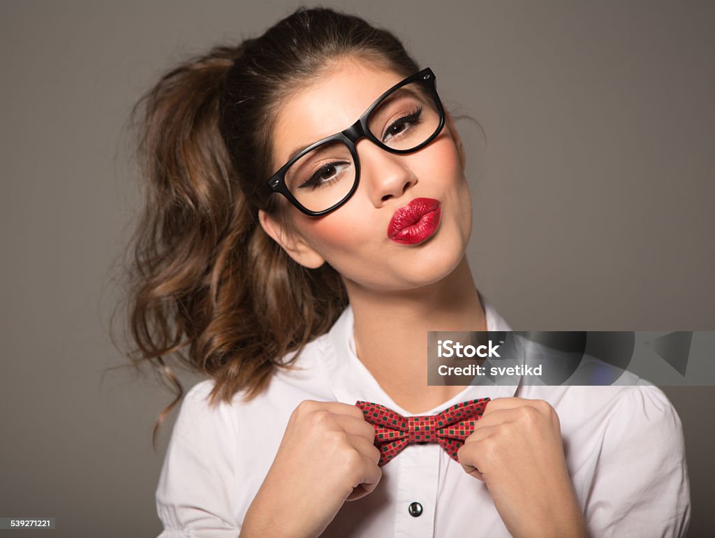 Brunette woman. Portrait of brunette woman wearing glasses and bow tie, looking at camera. Perfect skin and make up, healthy hair. Making faces. Eyeglasses Stock Photo