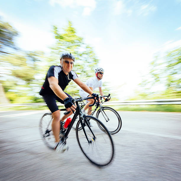 dois ciclistas em countryroad - racing bicycle cyclist sports race panning imagens e fotografias de stock