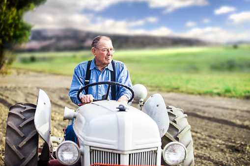 Portrait of real farmer riding tractor on his farm.