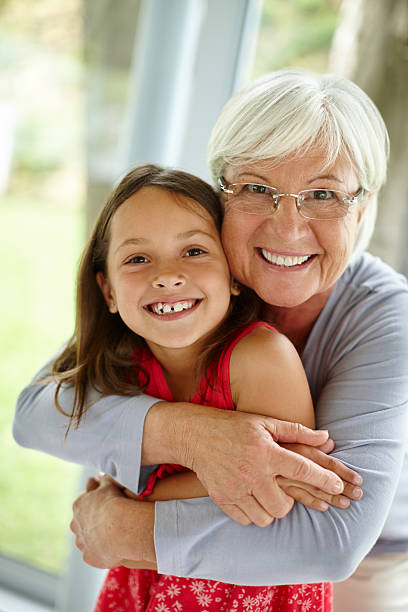 Loving cute granddaughter hugging her grandmother. Happy family.  Having good times with grandparent outdoors. Love, connection, bonding  concept