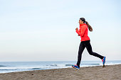 Serious Latino Woman Running on Beach