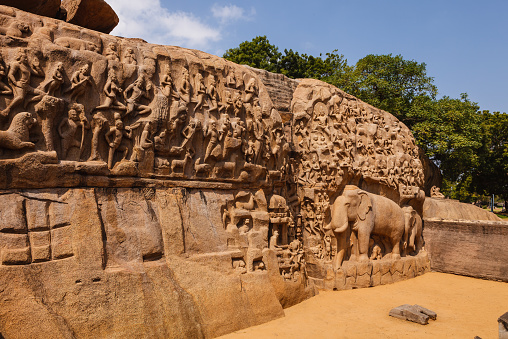 Descent of the Ganges, also known as Arjuna's penance, at Mahabalipuram or Mamallapuram, on the Coromandel Coast of the Bay of Bengal, in the Indian state of Tamil Nadu, India. Measuring 96 by 43 feet (29 m × 13 m), it is a giant open-air bas-relief carved out of two monolithic rocks. The legend depicted is the story of the descent of the sacred river, The Ganges to earth from the heavens led by Bhagiratha. In the old days, they had water running between the two rocks. The bas-relief is sculpture at its best, and not seen anywhere else in India. It survived the Tsunami of the 13th Century and the one of 2004. It is one of the Group of Monuments at Mahabalipuram that were designated as a UNESCO World Heritage Site in 1984. Photo shot in the afternoon sunlight; horizontal format. No people. Copy space.