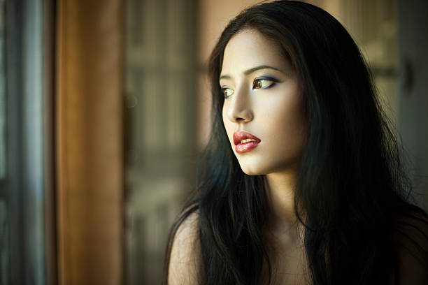 Beautiful young woman looking away through window.