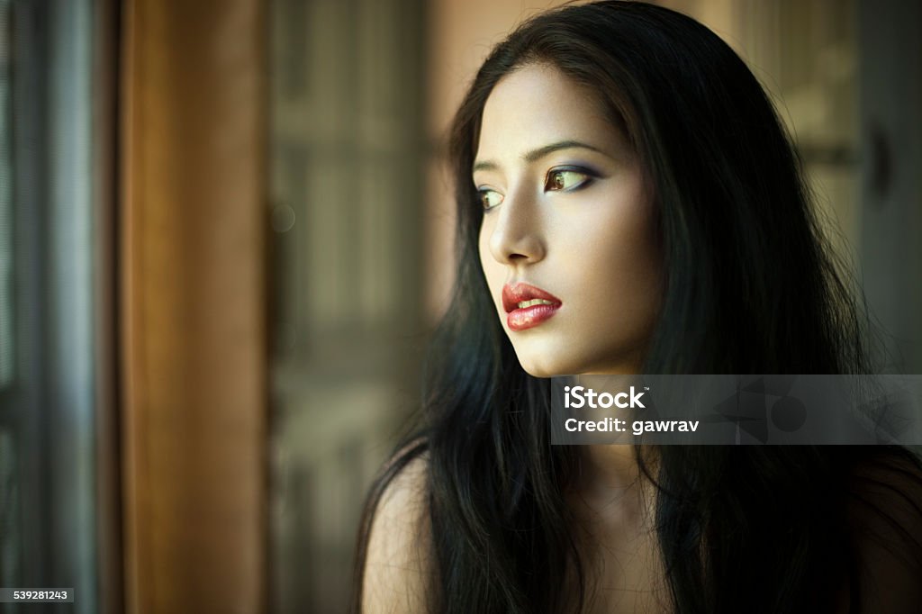 Beautiful young woman looking away through window. Beautiful Woman Stock Photo