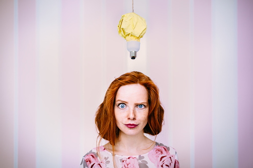 Thinking young woman with a floating lightbulb above her head