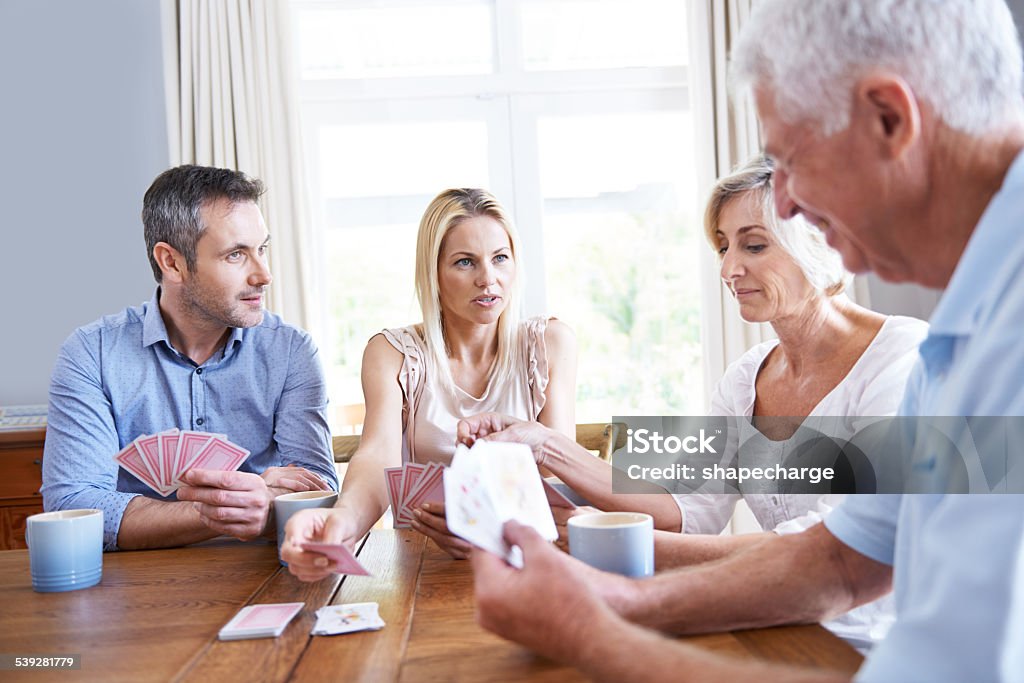 Read 'em and weep! Shot of a young couple playing cards with their parents at home 30-39 Years Stock Photo