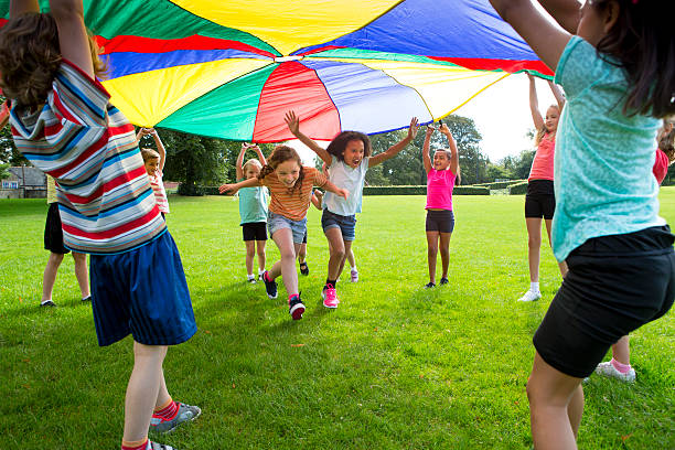 Outdoor Games Children playing a game with a colourful Parachute 8 9 years stock pictures, royalty-free photos & images