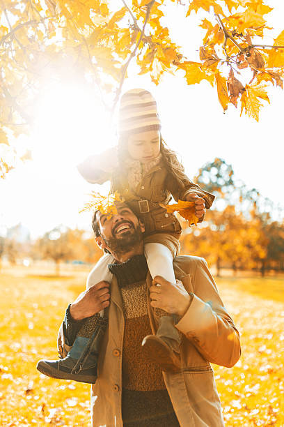 istock Father carrying his daughter on shoulders during autumn day. 539292893