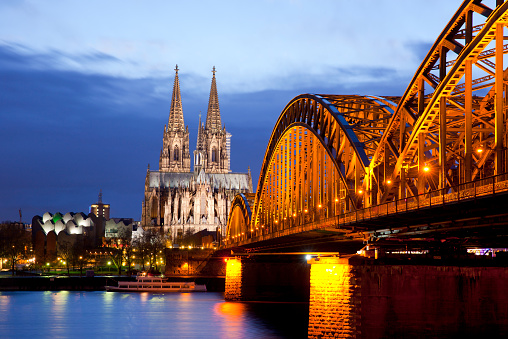 The illuminated Cologne Cathedral and Hohenzollern Bridge. Long exposure at night.
