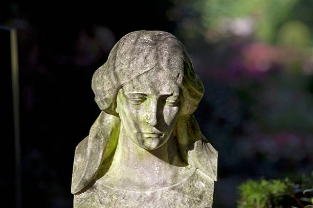 Statue of a young female subject surrounded by vegetation.