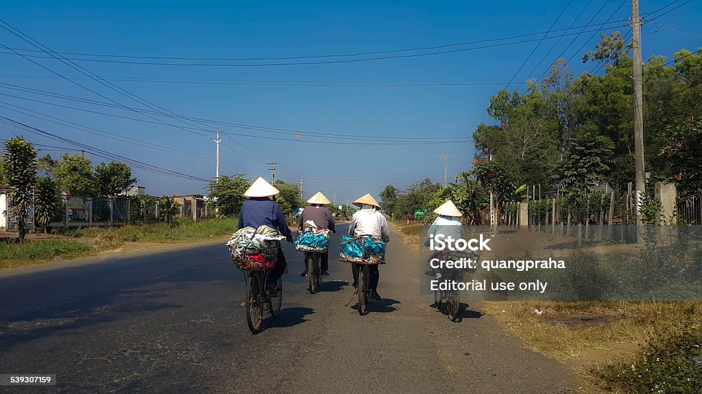 Four Vietnamese women on their  way to work Bao Loc town, Lam Dong province, Vietnam - February 11, 2015 - four women cycling under the sun for the purchase and sale of recyclable materials 2015 Stock Photo