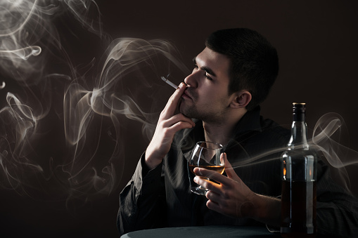 Serious African American Man smoking a cigarette against a dark background
