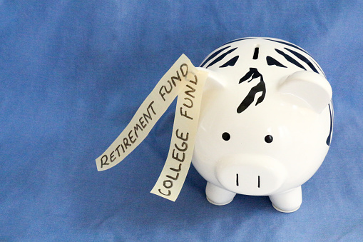 A zebra striped piggy bank is identified as both a college and a retirement fund.  Could represent having savings that are earmarked for multiple purposes.  The coin bank is isolated on blue.  The piggy bank is unusual as it is covered in black and white striped animal print.