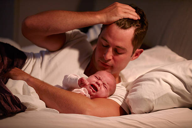 padre yacer en la cama con el llanto hija bebé - baby mother sleeping child fotografías e imágenes de stock