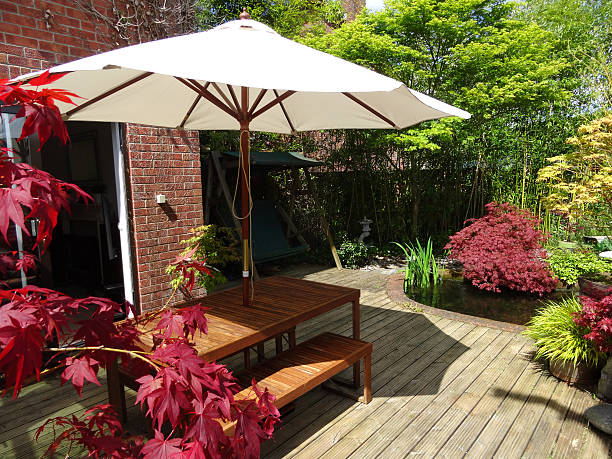 istock Image of garden decking with table and benches, cream-parasol, red-maples 539309137