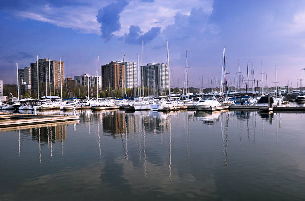 View of Bronte Harbour, on the shores of Lake Ontario, with city apartment buildings in the background and dark clouds of an approaching thunderstorm.