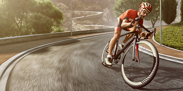 An athlete is riding a bicycle on a spirale track high in the mountains.  The man is wearing black bike shorts and shin guards along with a red sleeveless top and a red and white helmet and sunglasses.