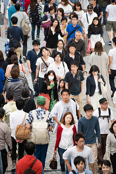 Elevated view of a large crowd of people walking along pavement in Shinjuku district of Tokyo, Japan. Large group of Japanese people.