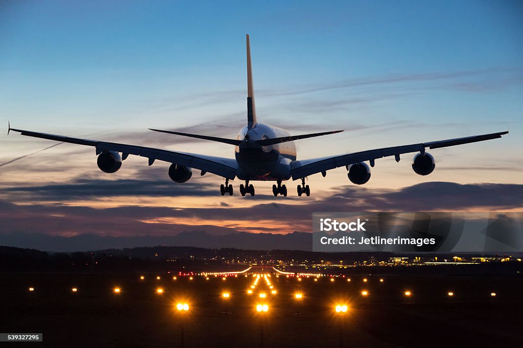 Landing airplane Photo of an airplane just before landing in the early morning. Runway lights can be seen in the foreground. Airplane Stock Photo