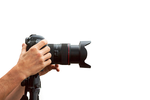 Side view of a DSLR camera on tripod in the hands of a photographer, isolated on white background, clipping path and copy space included