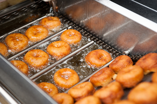 Deep frying doughnut machine close up