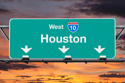 Houston Interstate 10 west highway sign with sunrise sky.