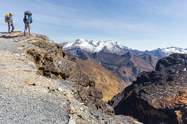 Backpackers tourists traveling standing walking hiking people walking mountain trail edge, El Choro trek, Cordillera real mountains canyon valley range ridge, Bolivia tourism.