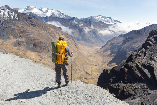 Backpacker tourist traveling standing walking hiking guy posing looking at mountain trail edge, El Choro trek, Cordillera real mountains canyon valley range ridge, Bolivia tourism.