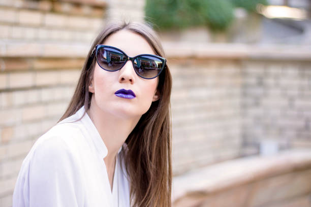 Young beautiful woman with black sunglasses looking at the you. Outdoor fashion portrait of young pretty woman in summer sunny day on street.