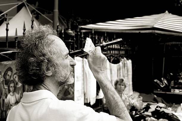 Palermo, Italy - October 22, 2006: A mature man testing an obsolete telescope or viewfinder by looking through it. The scene is captured in a weekly flea market of the Sicilian city. A woman, the owner of the market stall, is sitted down on the defocused background.
