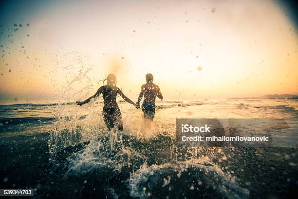 Couple Running In The Sea Stock Photo - Download Image Now - Beach, Sea, Couple - Relationship