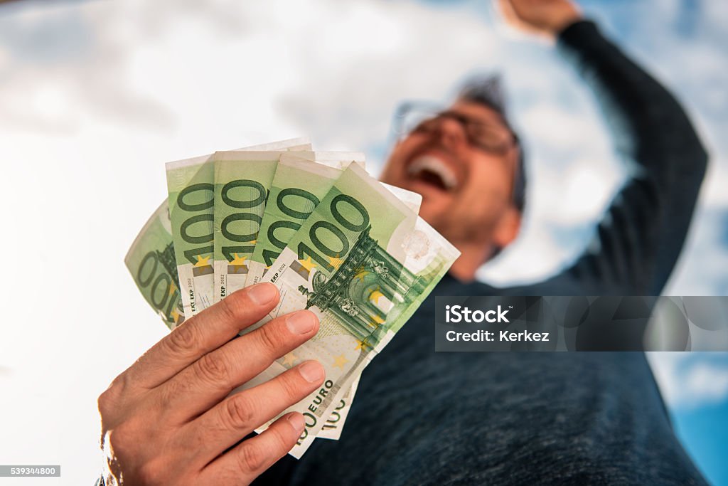 Man Holding Money Man with glasses wearing blue shirt. and holding stack of money. Currency Stock Photo