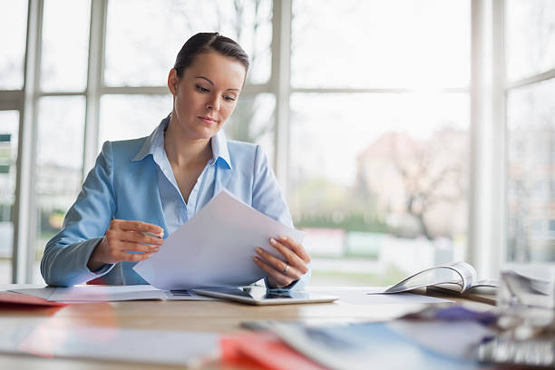 Young businesswoman reading document at office desk