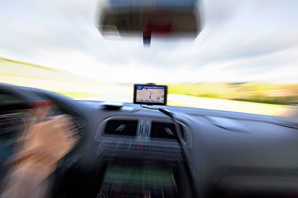 Woman is driving a car using car navigation. GPS receiver mounted on windscreen. Winter snow scenery