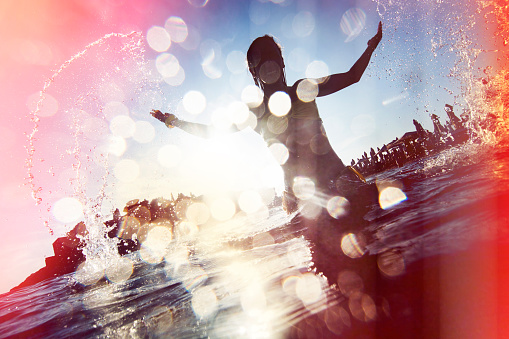 Silhouette of young woman splashing the water. Lomo Photo effect.