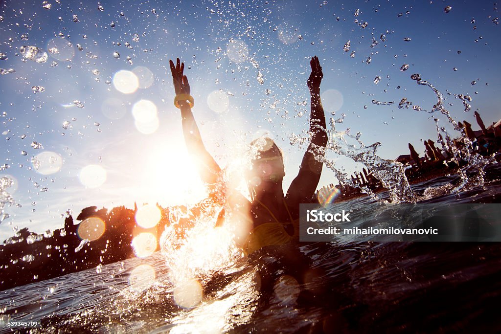 Young woman having fun Silhouette of young woman splashing the water Jumping Stock Photo